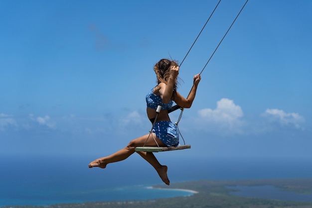 Foto jovem e bela mulher caucasiana no balanço da corda com o conceito de fundo do mar e do céu de férias e.