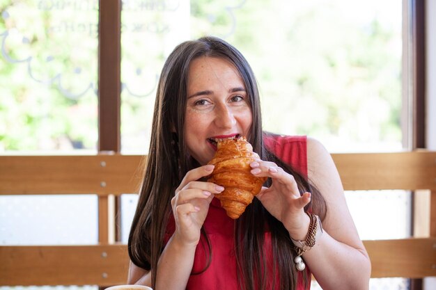 Jovem e bela mulher comendo croissant