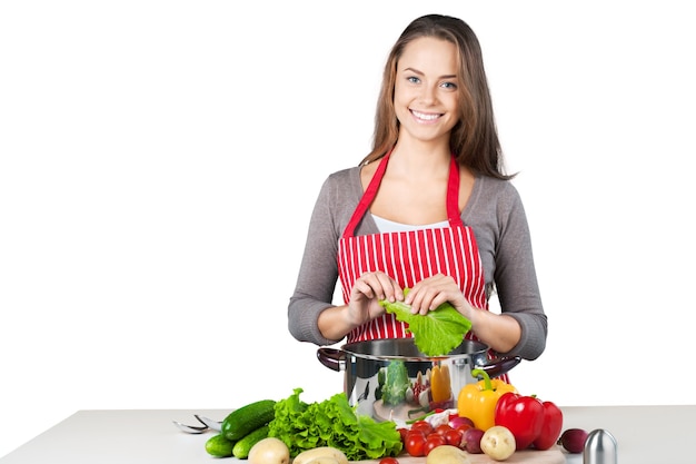 Jovem e bela mulher cozinhando em fundo branco