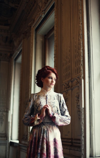 Foto jovem e bela mulher de pé na sala do palácio