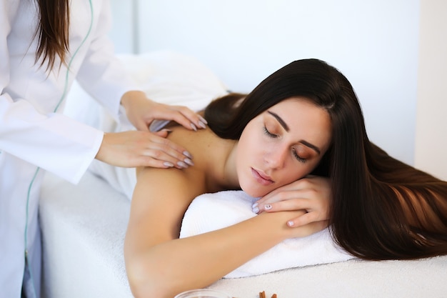 Jovem e bela mulher desfrutando de uma massagem na mesa no centro de spa.