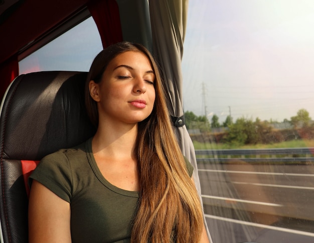 Jovem e bela mulher dormindo sentado no ônibus. Passageiro de ônibus viajando sentado em um assento e dormindo.