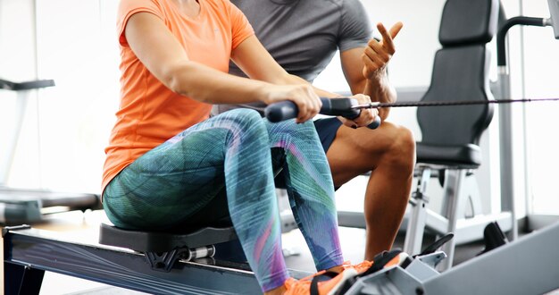 Jovem e bela mulher fazendo exercícios com o personal trainer na academia