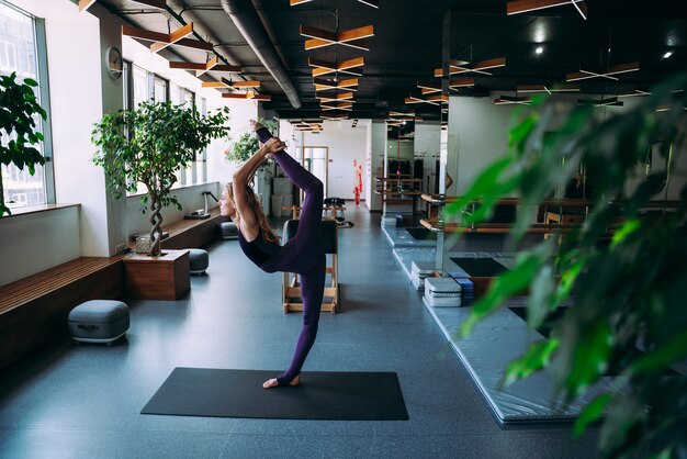 Jovem e bela mulher fazendo reabilitação física e pilates na academia