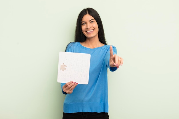 Jovem e bela mulher hispânica sorrindo com orgulho e confiança, fazendo o conceito de quebra-cabeça número um