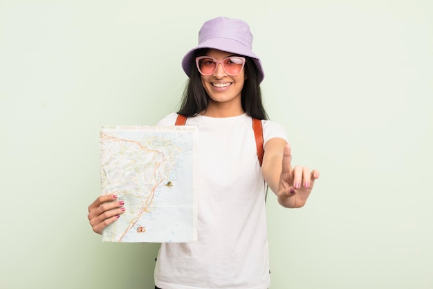 Jovem e bela mulher hispânica sorrindo com orgulho e confiança, tornando o conceito de turista e mapa número um