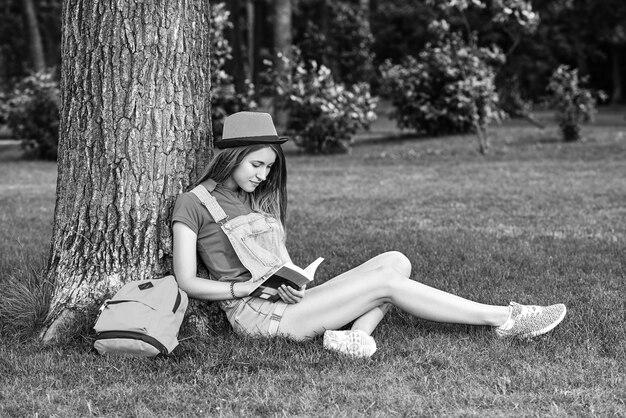 Jovem e bela mulher lendo livro no parque