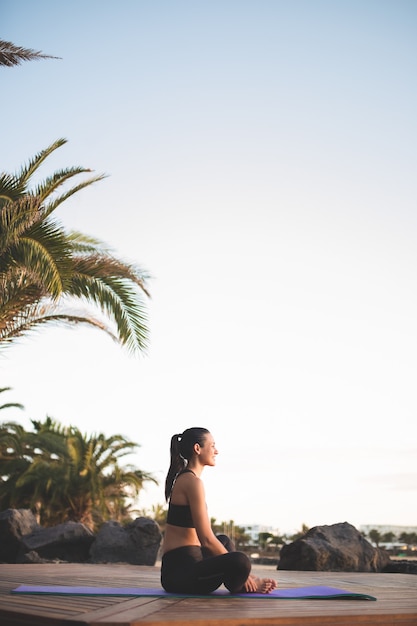 Jovem e bela mulher meditando ao ar livre ao nascer do sol