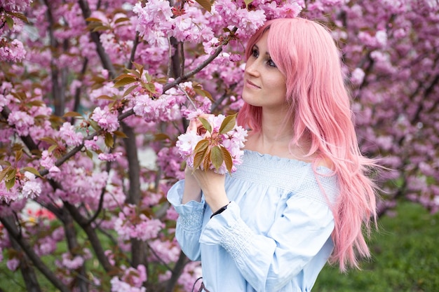 Jovem e bela mulher perto da árvore florescendo de sakura Flores cor de rosa primavera e conceito de juventude Menina elegante sorrindo Jardim florescente com cerejeira