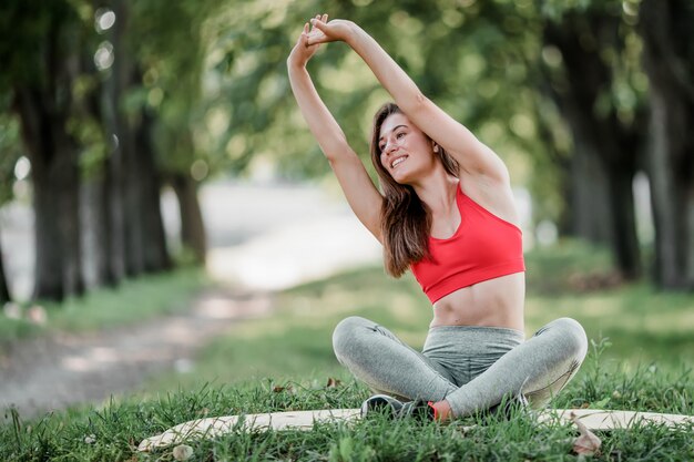 Jovem e bela mulher praticando ioga no parque verde