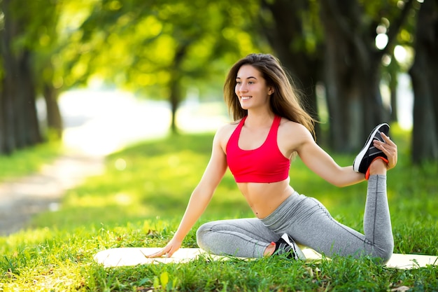 Jovem e bela mulher praticando ioga no parque verde