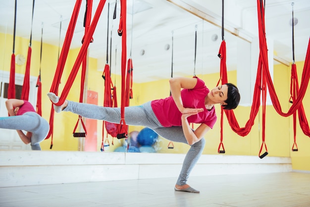 Jovem e bela mulher praticando ioga voe com uma rede. voar, fitness, alongamento, equilíbrio, exercício.