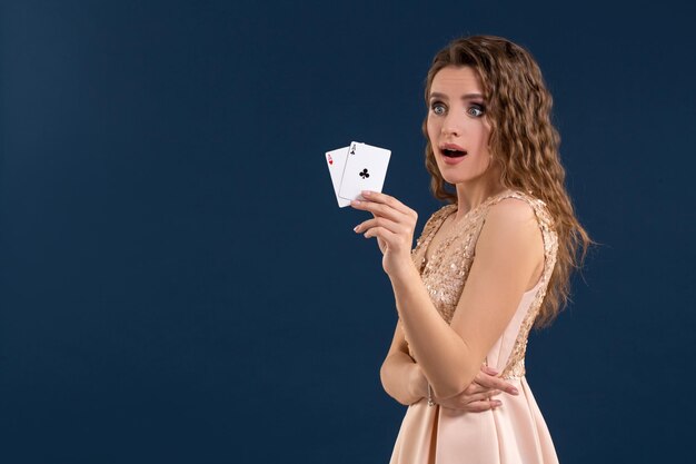 Jovem e bela mulher segurando a combinação vencedora de cartas de pôquer em fundo azul escuro. Dois ases