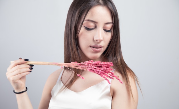 Jovem e bela mulher segurando grama rosa.