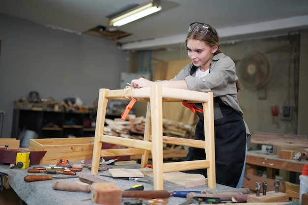 Jovem e bela mulher trabalhando na sala de oficina de carpinteiro DIY. Proprietário de pequena empresa, jovem que trabalha na fábrica de móveis.