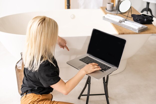 Jovem e bela mulher usando um computador portátil em casa.