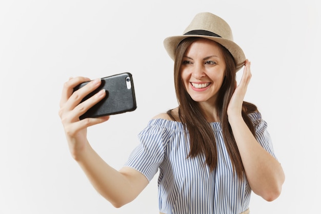 Jovem e bela mulher vestida de vestido azul, chapéu fazendo selfie filmado no celular ou videochamada isolada no fundo branco. Pessoas, emoções sinceras, conceito de estilo de vida. Área de publicidade. Copie o espaço.