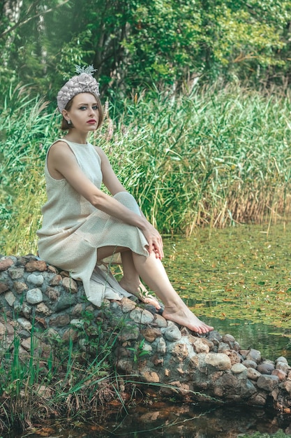 Jovem e bela sereia com coroa de conchas está sentada no fundo da água. Cosplay de sereia.