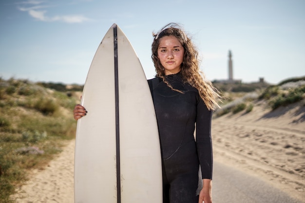 Foto jovem e bela surfista na praia ao pôr do sol