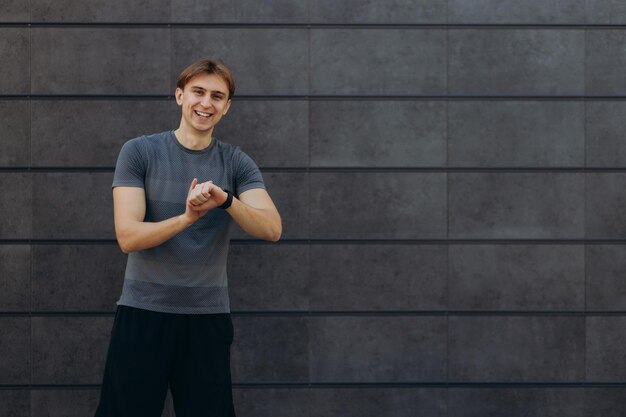 Jovem e belo homem desportivo posando ao ar livre no fundo simples da manhã