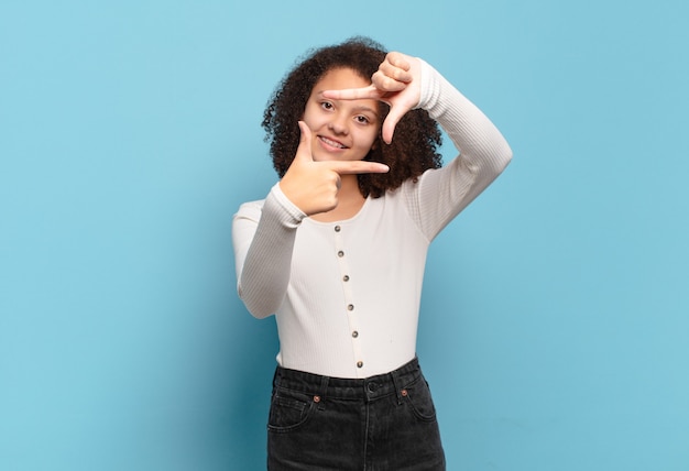 Jovem e bonita afro fazendo molduras com as mãos