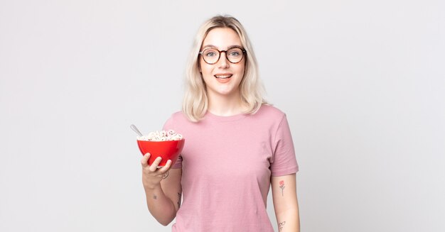 jovem e bonita albina parecendo feliz e agradavelmente surpresa com uma tigela de café da manhã