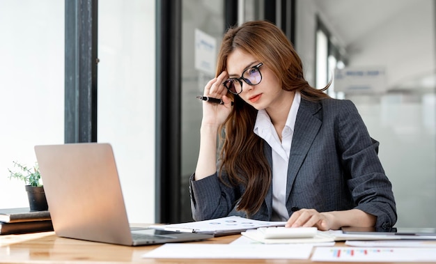 Jovem e bonita empresária branca ocupada sofrendo de estresse trabalhando no computador do escritório