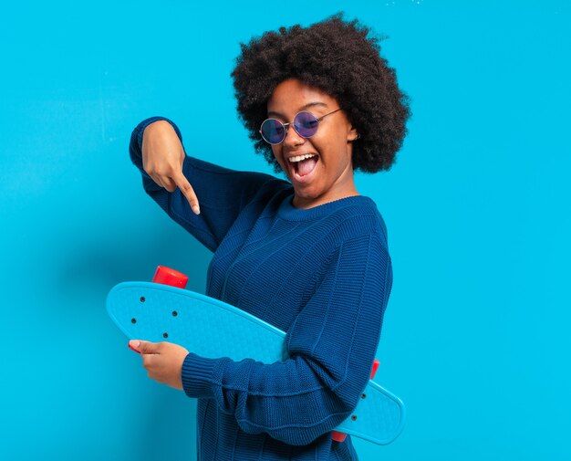 Jovem e bonita mulher afro com uma prancha de skate