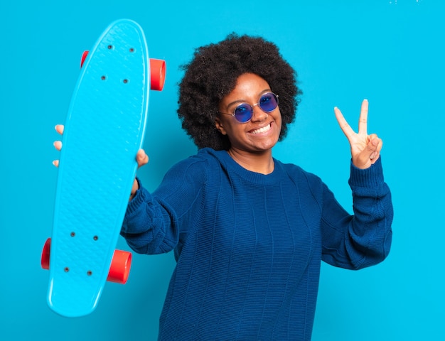 Foto jovem e bonita mulher afro com uma prancha de skate