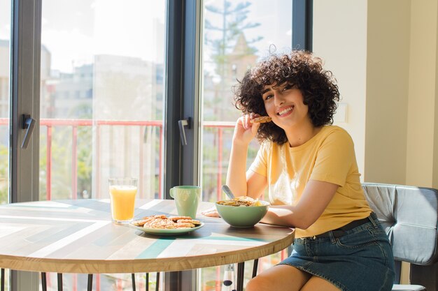 Foto jovem e bonita mulher árabe tomando café da manhã em casa