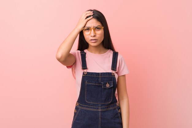 Jovem e bonita mulher árabe vestindo jeans cansado e muito sonolento, mantendo a mão na cabeça.