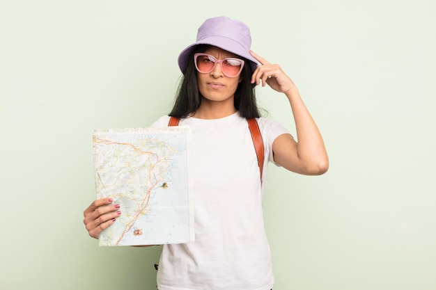 Jovem e bonita mulher hispânica se sentindo confusa e confusa, mostrando que você é um turista insano e um conceito de mapa