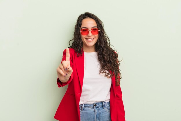 Jovem e bonita mulher hispânica sorrindo e parecendo amigável, mostrando a empresária legal número um