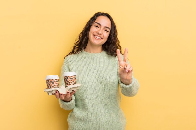 Jovem e bonita mulher hispânica sorrindo e parecendo amigável mostrando o conceito de café para tirar o número dois