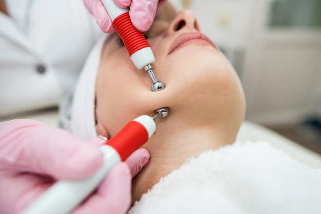 Foto jovem e bonita mulher recebe procedimento de terapia de microcorrentes na clínica de beleza