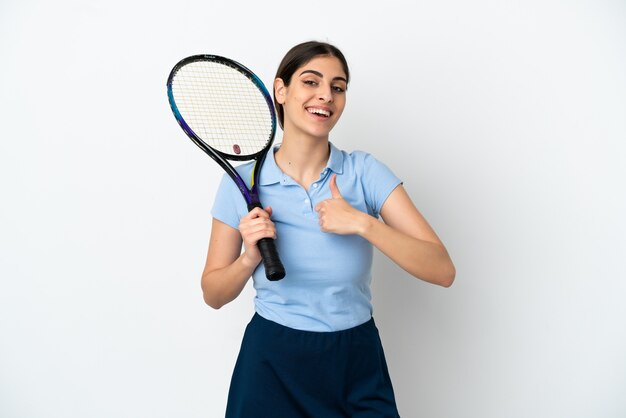 Jovem e bonita tenista caucasiana isolada na parede branca fazendo um gesto de polegar para cima