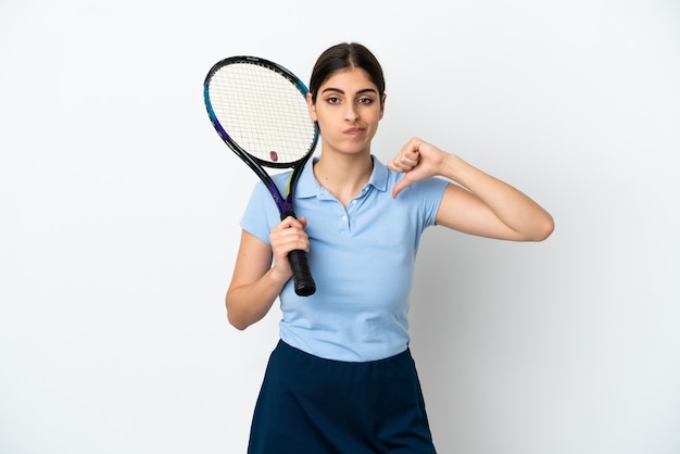 Jovem e bonita tenista caucasiana isolada no fundo branco, mostrando o polegar para baixo com expressão negativa