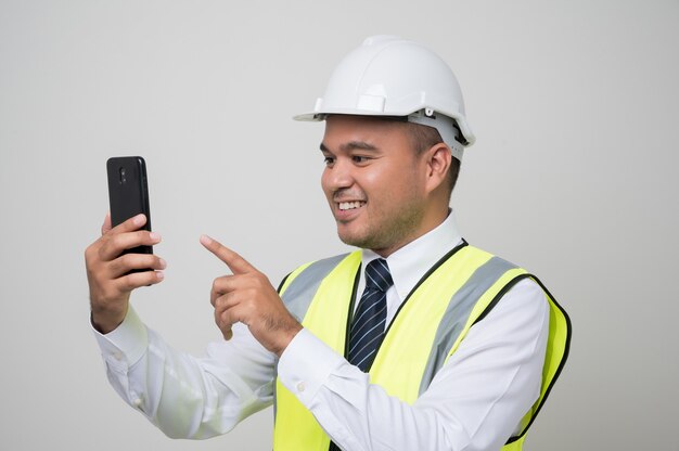 Jovem e bonito engenheiro civil asiático com um telefone