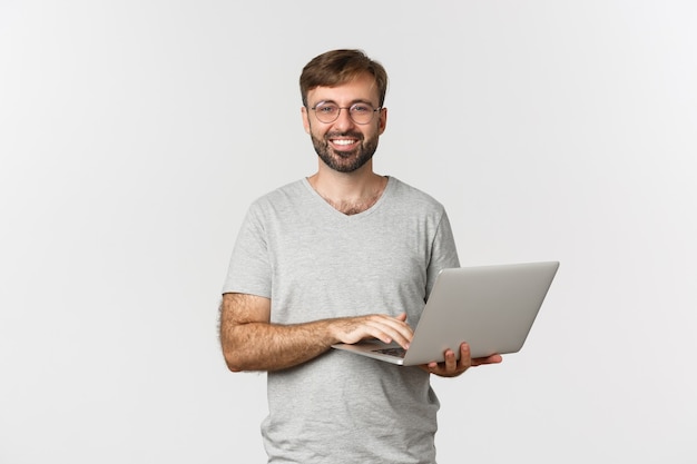 Foto jovem e bonito freelancer de óculos e camiseta cinza