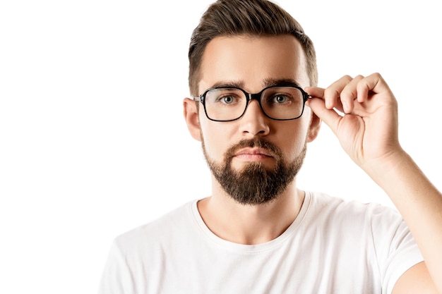 Jovem e bonito homem barbudo usando óculos no fundo branco