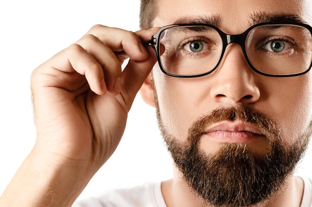 Jovem e bonito homem barbudo usando óculos no fundo branco