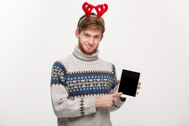 Jovem e bonito mostrando a exibição e apontar o tablet.