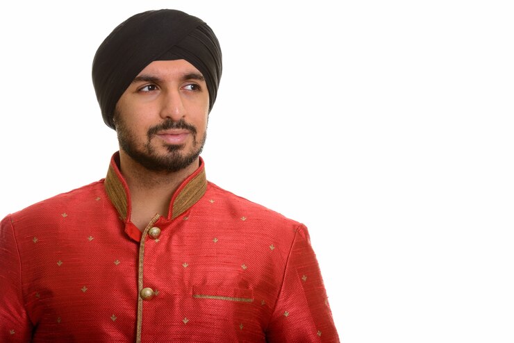 Foto jovem e bonito sikh indiano pensando enquanto usa roupa tradicional