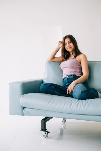 Foto jovem e calma mulher caucasiana relaxando, sentada no sofá na moderna sala de estar