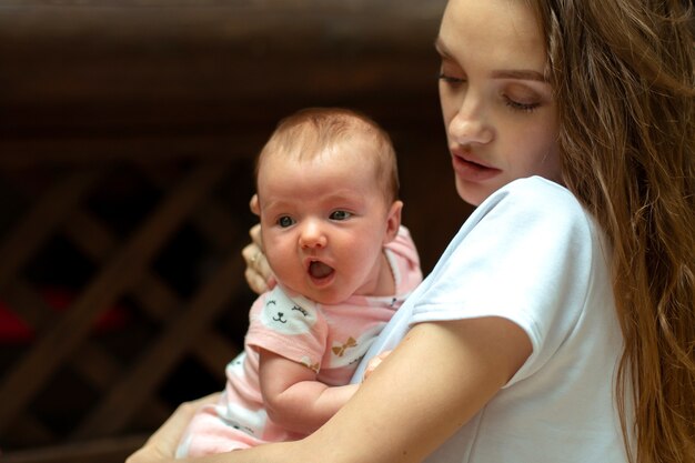 Jovem e encantadora mãe com uma menina nas mãos