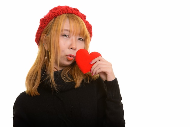 Jovem e fofa mulher asiática segurando e beijando um coração vermelho