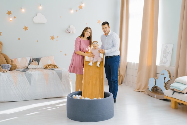 Jovem e linda família posando com a filha no quarto das crianças