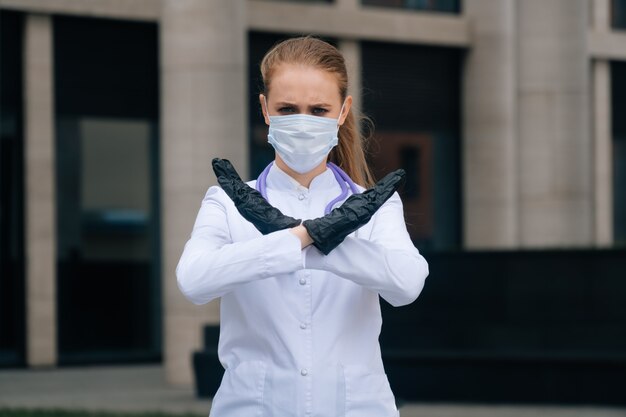 Jovem e linda médica com máscara de proteção e luvas