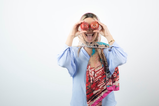 Jovem e linda modelo com um xale colorido segurando uma maçã vermelha na frente dos olhos