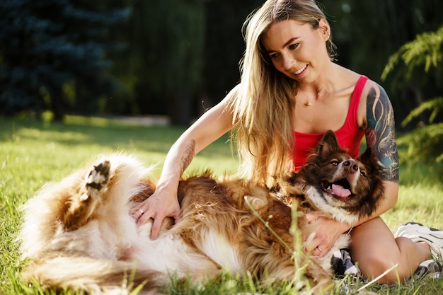 Foto jovem e linda mulher acariciando seu lindo cachorro no parque